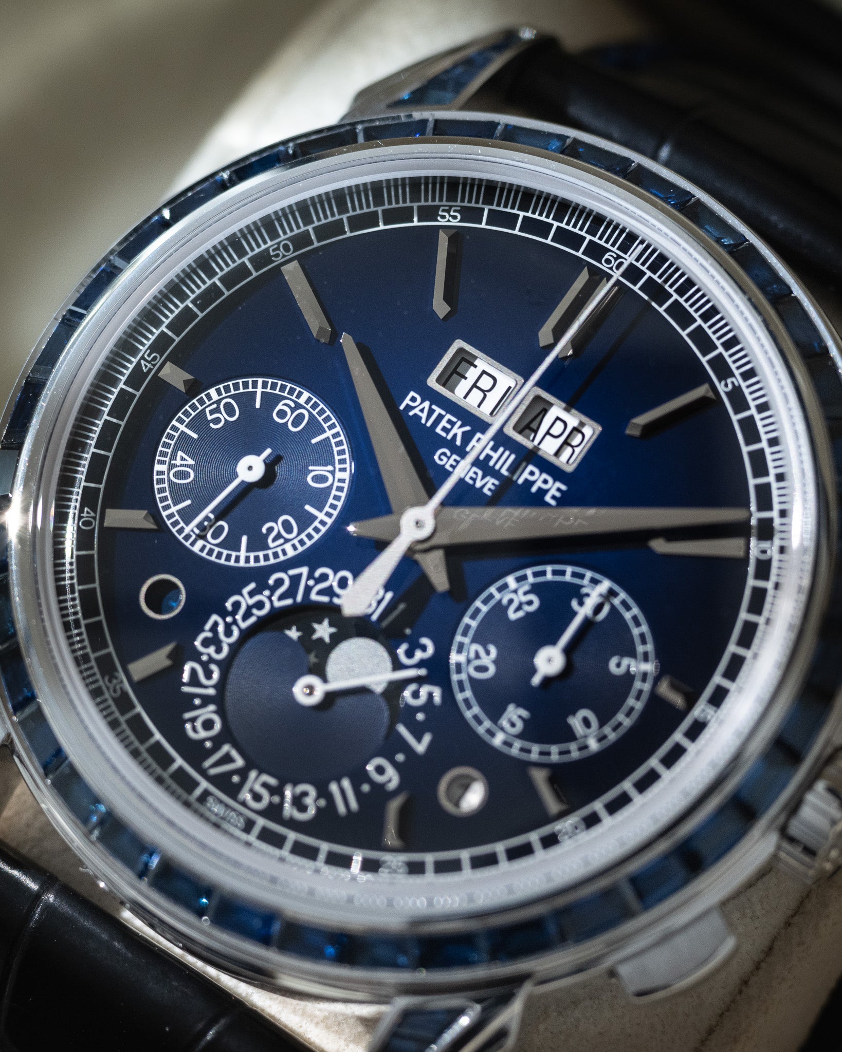 Close-up of a Patek Philippe watch with a blue face and black strap.